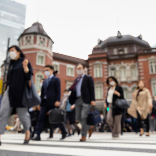 東京駅前の横断歩道をマスクをつけて歩く人々