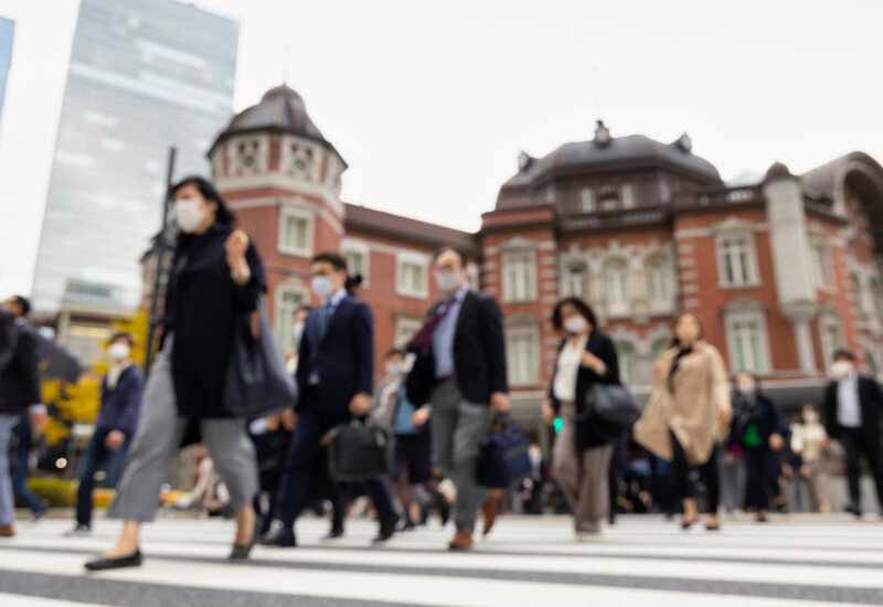 東京駅前の横断歩道をマスクをつけて歩く人々
